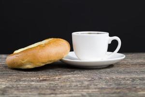 um delicioso pão fresco e uma xícara de café preto aromático foto