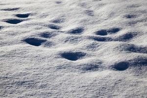 pegadas e amassados na neve depois que as pessoas passaram foto