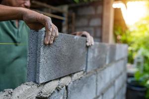 trabalhador de mãos de close-up usa construção de bloco de tijolos foto