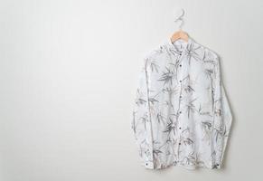 camisa pendurada com cabide de madeira na parede foto