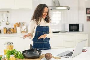 mulher latina gravando vídeo e cozinhando na cozinha foto