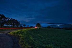 estrada com árvores e prados na hora azul à noite foto