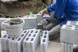 mão de construtor segurando um bloco de concreto para construir uma cerca para uma casa de campo. foto