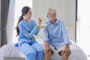 enfermeira do hospício está alimentando comida de mingau para homem caucasiano no centro de aposentadoria de pensão para reabilitação de cuidados domiciliares e processo de recuperação pós-tratamento foto