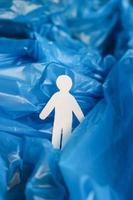 a silhueta de um homem esculpida em papel branco está imersa em um saco plástico azul como se estivesse em ondas de água, oceano, mar.