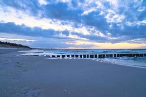 pôr do sol na praia do mar Báltico. groynes chegar ao mar. hora azul foto