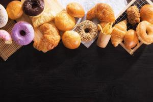 Vários tipos de junk food na mesa de madeira preta de vista superior com espaço de cópia. foto