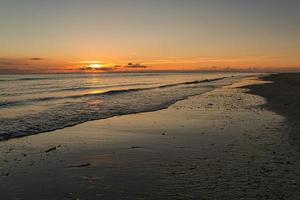 pôr do sol na praia de blavand na dinamarca. andando à noite em grande atmosfera de luz foto
