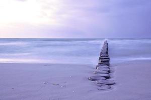 groynes que se projetam no horizonte no mar Báltico. longa exposição com cores suaves. foto