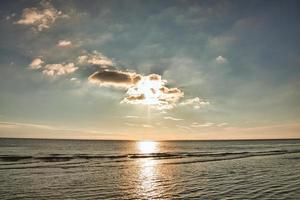 pôr do sol no estande da blavand dinamarca. horas da noite em clima de luz quente foto