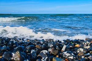 na praia do mar Báltico com muitas pedras. além disso ondas rolando na praia foto