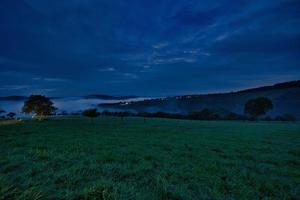 estrada com árvores e prados na hora azul à noite. foto