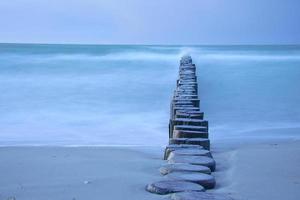 groynes que se projetam no horizonte no mar Báltico. longa exposição com cores suaves. foto