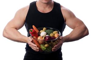 homem musculoso segurando frutas e legumes foto