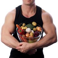 homem de comida crua segurando legumes e frutas foto