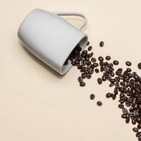 grãos de café e xícara branca em fundo colorido foto