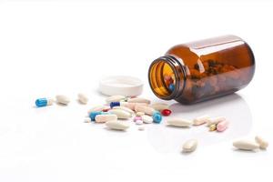 closeup em cápsulas de comprimidos saindo do frasco de comprimidos isolado em um conceito de fundo, saúde e drogas médicas foto