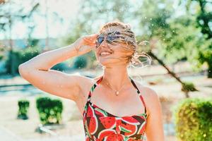 rindo mulher loira emocional com cabelo molhado fazendo salpicos de água. férias, felicidade, diversão, verão, conceito de lazer foto