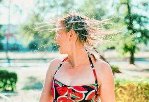 rindo mulher loira emocional com cabelo molhado fazendo salpicos de água. férias, felicidade, diversão, verão, conceito de lazer foto