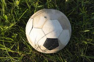 uma velha bola de futebol está na grama, close-up foto