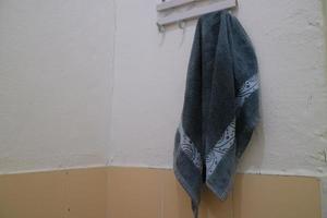 toalha molhada azul escura pendurada na parede do banheiro foto