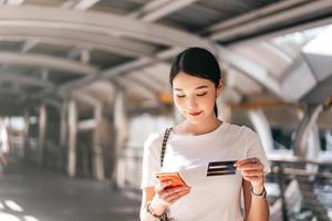 consumidor de mulher asiática de negócios adultos jovens usando cartão de crédito e smartphone para compras on-line. foto