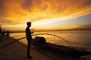 um povo em pé no mar contra o céu durante o pôr do sol foto