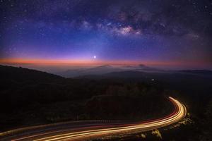 galáxia da via láctea com iluminação na estrada em doi inthanon chiang mai, tailândia. fotografia de longa exposição. com grão foto