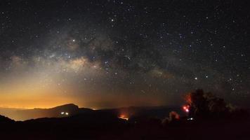 panorama Via Láctea com cidade clara em doi inthanon chiang mai, tailândia. fotografia de longa exposição. com grão foto