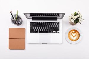 vista superior laptop ou escritório de espaço de trabalho de notebook e café com leite na mesa branca foto