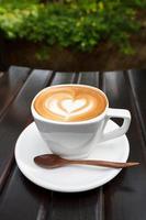 xícara de café com leite na mesa de madeira foto