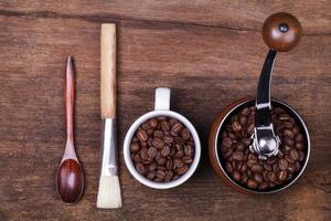 xícara de grãos de café e colher no fundo de madeira marrom foto