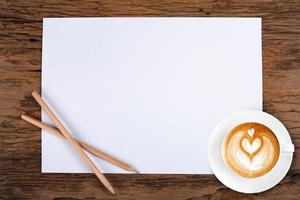 papel em branco com lápis e uma xícara de café em madeira foto