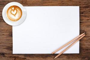 papel em branco com lápis e uma xícara de café em madeira foto