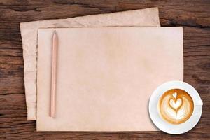 papel em branco com lápis e uma xícara de café em madeira foto