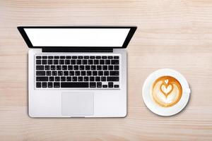 xícara de vista superior de café com leite e notebook de computador portátil na mesa de madeira foto