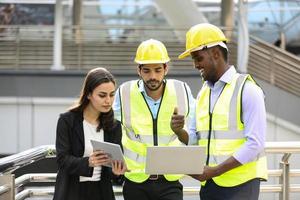 um homem industrial e engenheiros de mulher com tablet no canteiro de obras verificando documentos. foto