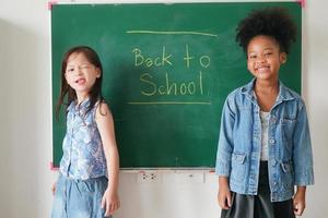 meninas felizes contra a lousa com volta às aulas foto