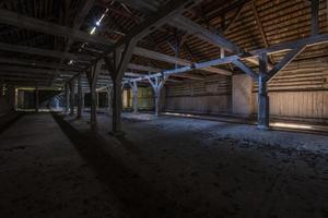 dentro do hangar em decomposição de madeira arruinado escuro abandonado com colunas apodrecidas foto