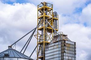 elevador do celeiro. silos de prata em agro-processamento e planta de fabricação para processamento de secagem, limpeza e armazenamento de produtos agrícolas, farinhas, cereais e grãos. foto