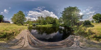 panorama hdri esférico sem costura completo vista de ângulo de 360 graus no cais de madeira do lago ou rio perto da ponte com belas nuvens em projeção equirretangular, conteúdo vr foto