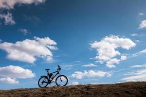 silhueta de bicicleta no céu azul com nuvens. símbolo de independência e liberdade foto