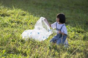 crianças asiáticas se voluntariam para colocar garrafas plásticas em sacos de lixo. conceito voluntário e ecologia foto