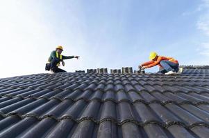 uma equipe de trabalhadores da construção civil em roupas de trabalho instalou novos equipamentos de cobertura. ferramentas para telhados, furadeira elétrica e usá-lo em novos telhados de madeira com chapas de metal. foto