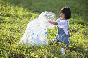 crianças asiáticas se voluntariam para colocar garrafas plásticas em sacos de lixo. conceito voluntário e ecologia