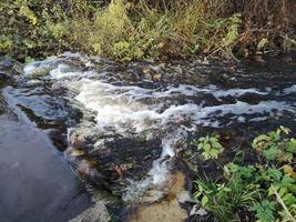 forte corrente em um pequeno rio. corredeiras na água foto