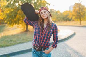 retrato de uma menina bonita com um skate na mão, ao ar livre foto