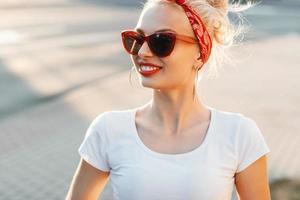 mulher bonita hipster com lábios vermelhos e óculos de sol no meio da rua. foto