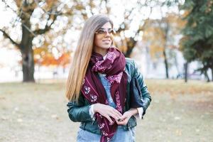 retrato de uma linda garota de óculos escuros, cachecol e jaqueta no parque outono foto