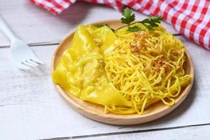 macarrão amarelo na chapa branca e bolinhos de carne de porco fundo de madeira, macarrão instantâneo macarrão amarelo arroz aletria comida com alho frito foto